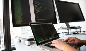 Osoba pisze kod na laptopie, przygotowując się do rozmowy o pracę z pytaniami rekrutacyjnymi dotyczącymi Angulara.