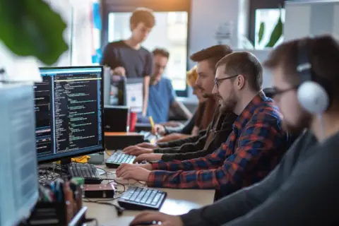 Zespół programistów pracuje nad oprogramowaniem business intelligence. Analiza danych i kodowanie na monitorach.