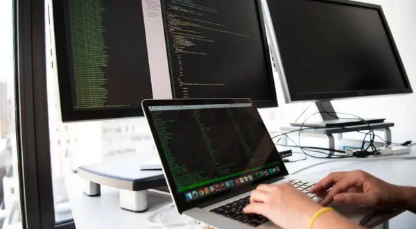 Osoba pisze kod na laptopie, przygotowując się do rozmowy o pracę z pytaniami rekrutacyjnymi dotyczącymi Angulara.