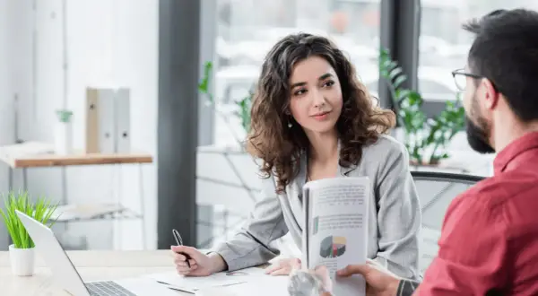 Kobieta i mężczyzna omawiają wykresy w nowoczesnym biurze, symbolizując efektywny digital workplace.