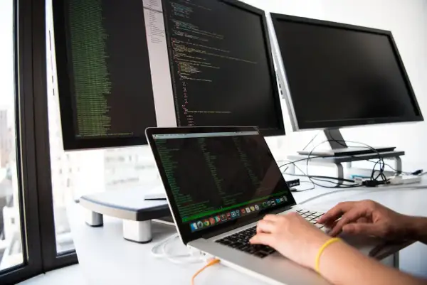 Osoba pisze kod na laptopie, przygotowując się do rozmowy o pracę z pytaniami rekrutacyjnymi dotyczącymi Angulara.