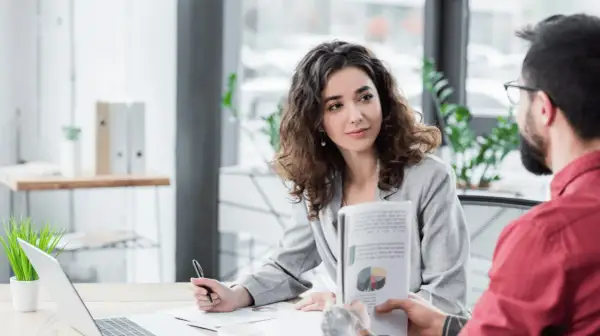 Kobieta i mężczyzna omawiają wykresy w nowoczesnym biurze, symbolizując efektywny digital workplace.